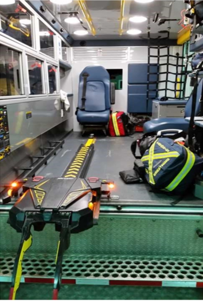 The scene was the confined quarters of the back of the ambulance. The gurney was situated along the left side of the ambulance.