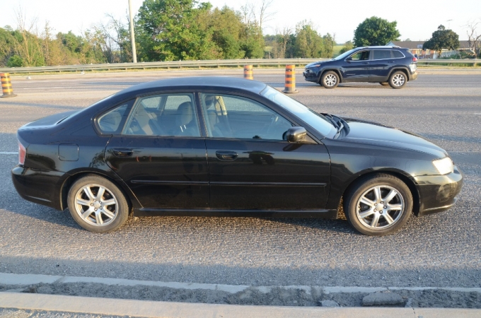 La voiture Subaru éraflée sur le côté par la Scion rouge sur la bretelle de sortie. Les dommages sont apparents sur le pare-chocs avant du côté passager. Le véhicule Jeep conduit par l’AI est à l’arrière-plan de la photo. Il n’a pas été touché dans la collision et n’a pas subi de dommages.