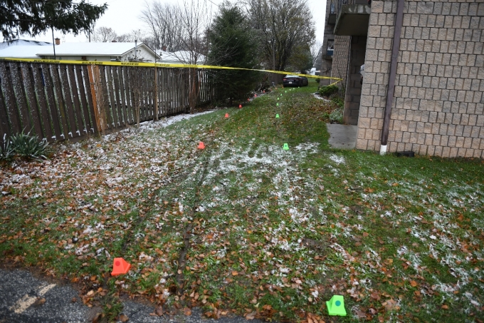 The grassy yard running behind 53 McNaughton Avenue West where the collision occured. Green and orange evidence markers mark the tire tracks of the CKPS cruiser (visible in the distance) which struck the Complainant.