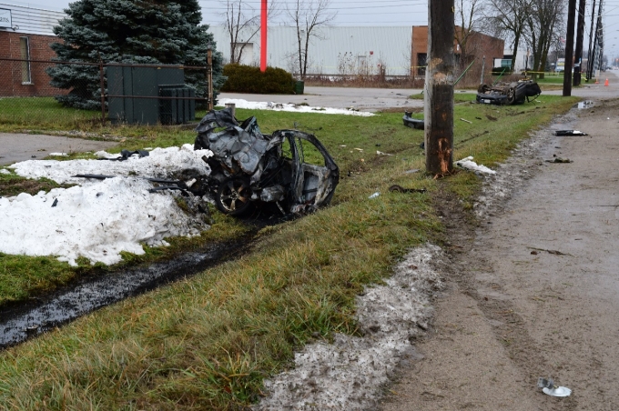 Traces de pneu visibles se rendant jusqu’à un poteau d’électricité endommagé. La partie arrière du véhicule Mazda est en avant-plan. Elle a laissé des traces d’incendie sur le sol à proximité. La partie avant de la Mazda repose sur le toit en arrière-plan, et des débris du véhicule sont dispersés dans le secteur.