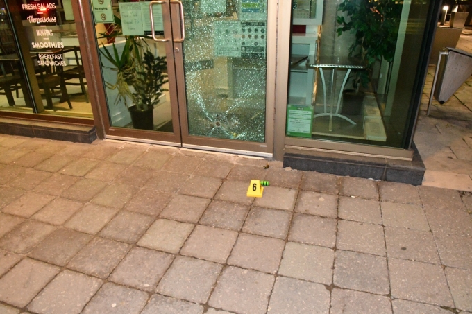Figure 2 - An ARWEN projectile, indicated by a yellow evidence marker, in front of the Presse Café's glass door which was damaged during the incident.