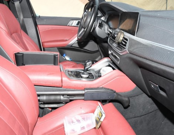 Figure 5 - Int&eacute;rieur de la BMW avec un fusil de chasse visible pr&egrave;s de la console centrale.