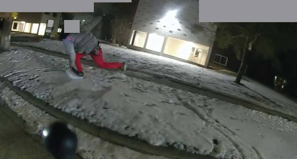 Figure 7 - Screenshot from BWC footage, depicting the Complainant crouching or falling forward, and stumbling, towards WO #2 with the machete raised in his right hand.  This still captures the approximate moment a gunshot was heard.
